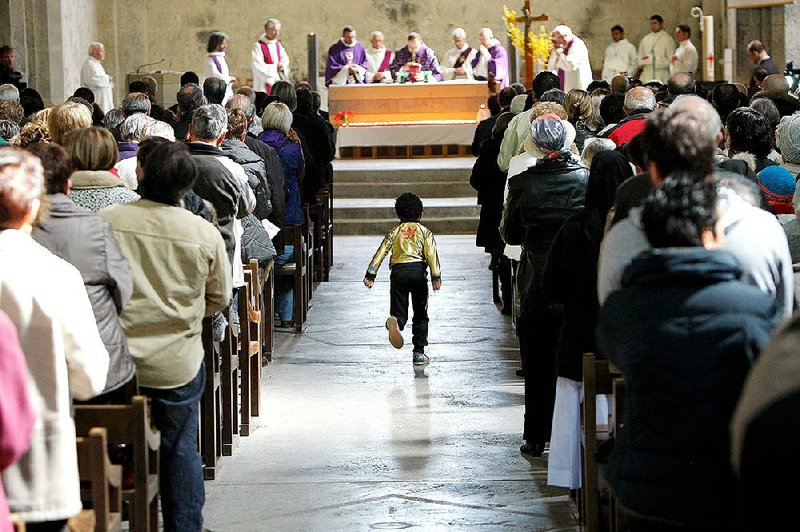 A child scampers down the aisle Saturday during a special Mass for the victims of the Germanwings crash at the cathedral Notre Dame de Bourg in Digne-les-Bains, France. 