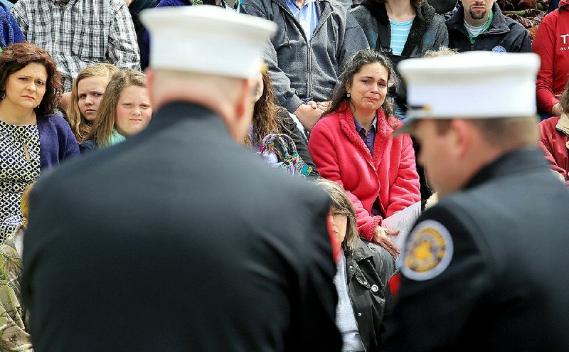 Pam Hutton Greene (left) and her sister Angela Hutton McBride (center) watch as two firefighters ring a bell, then read the name of their father, J.B. Hutton Jr., during Saturday’s service at the Arkansas Fallen Firefighters Memorial on the grounds of the state Capitol.