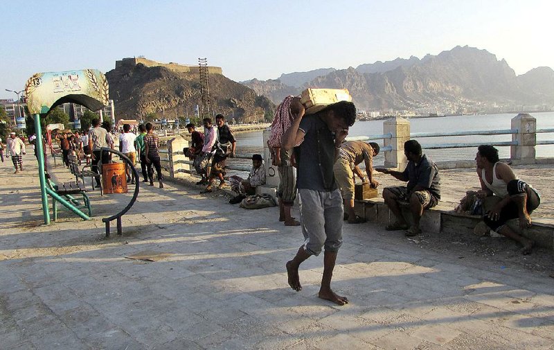 A Yemeni man carries away a box of ammunition looted from a military depot Friday in Aden. 