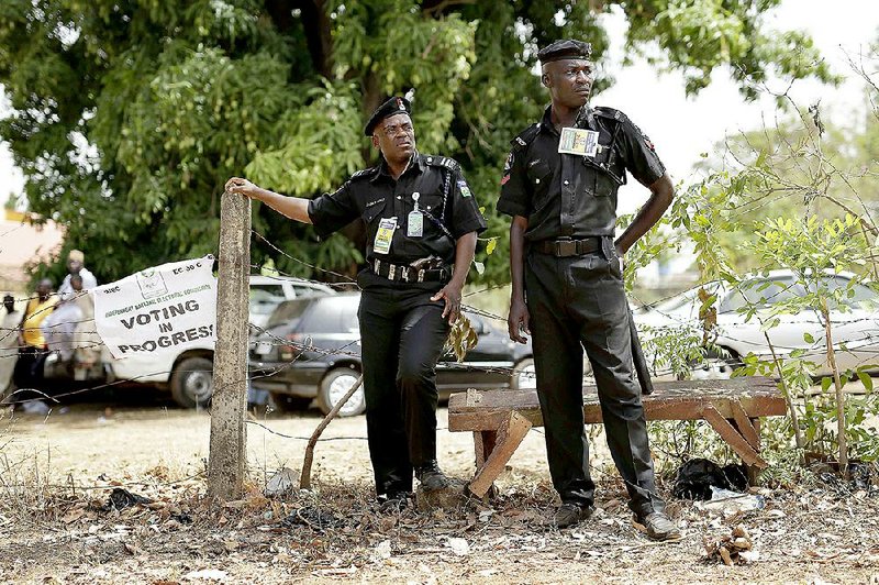 Police officers in Kaduna, Nigeria, keep watch Saturday as people line up to vote in presidential and legislative elections.