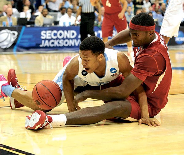 NWA Democrat-Gazette/Michael Woods RUMINATING RAZORBACKS: Arkansas forward Bobby Portis and North Carolina guard Nate Britt get tangled up going after a loose ball during the first half of an NCAA third-round game March 21 at Veterans Memorial Arena in Jacksonville, Fla. Southeastern Conference player of the year Portis and teammate Michael Qualls continue to weigh their NBA options after standout underclassman campaigns.