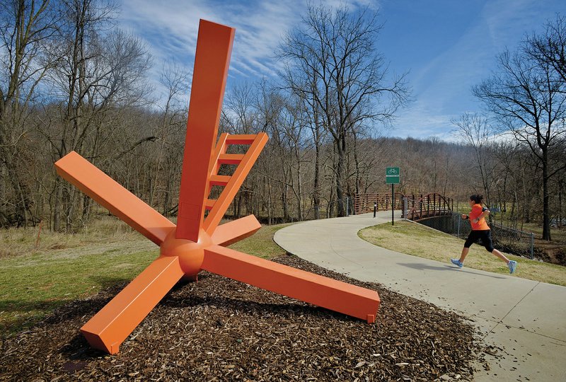 NWA Democrat-Gazette/BEN GOFF &#8212; 03/12/15 &#8212; A runner passes &#8216;SunKissed&#8217; by Nathan Pierce, a sculpture echoing the intersecting lines at the &#8216;Y&#8217; on the North Bentonville Trail on March 12. Bentonville was the second large city in the area to create a formal process for accepting public art.