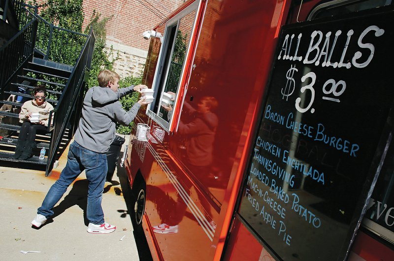 NWA Media/DAVID GOTTSCHALK - 10/14/14 - Carley Arnold (left) and Sean Kirkpatrick collect their order from the window of Baller Food Truck at 2 N. College Avenue in Fayetteville last fall. The Baller Food Truck is run by brothers Kyle and Kurt Young and features all menu items in the shape of a ball.