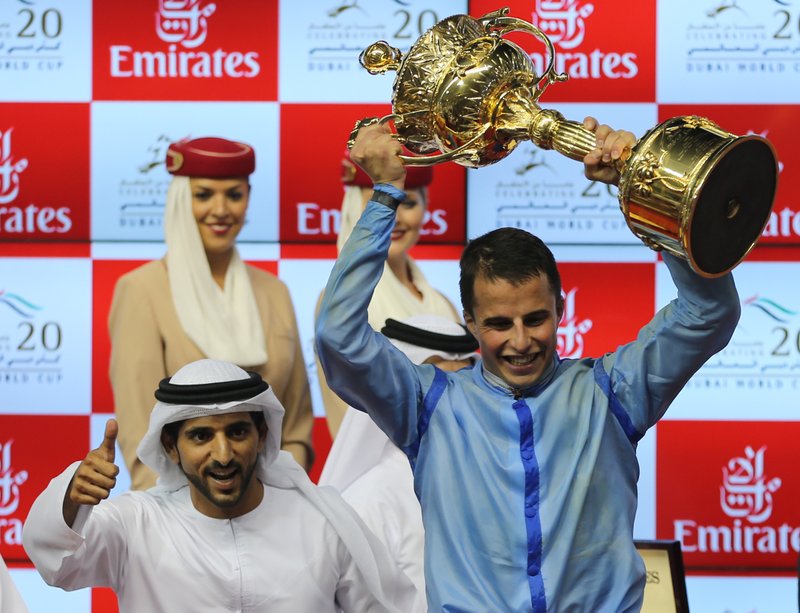 William Buick, jockey of Prince Bishop holds the trophy as he celebrates with the owner, Dubai crown Prince Sheik Hamdan bin Mohammed Al Maktoum, left, after winning the $ 10,000,000 Dubai World Cup,  during the Dubai World Cup horse racing event, at Meydan Racecourse in Dubai, United Arab Emirates, Saturday, March 28, 2015.