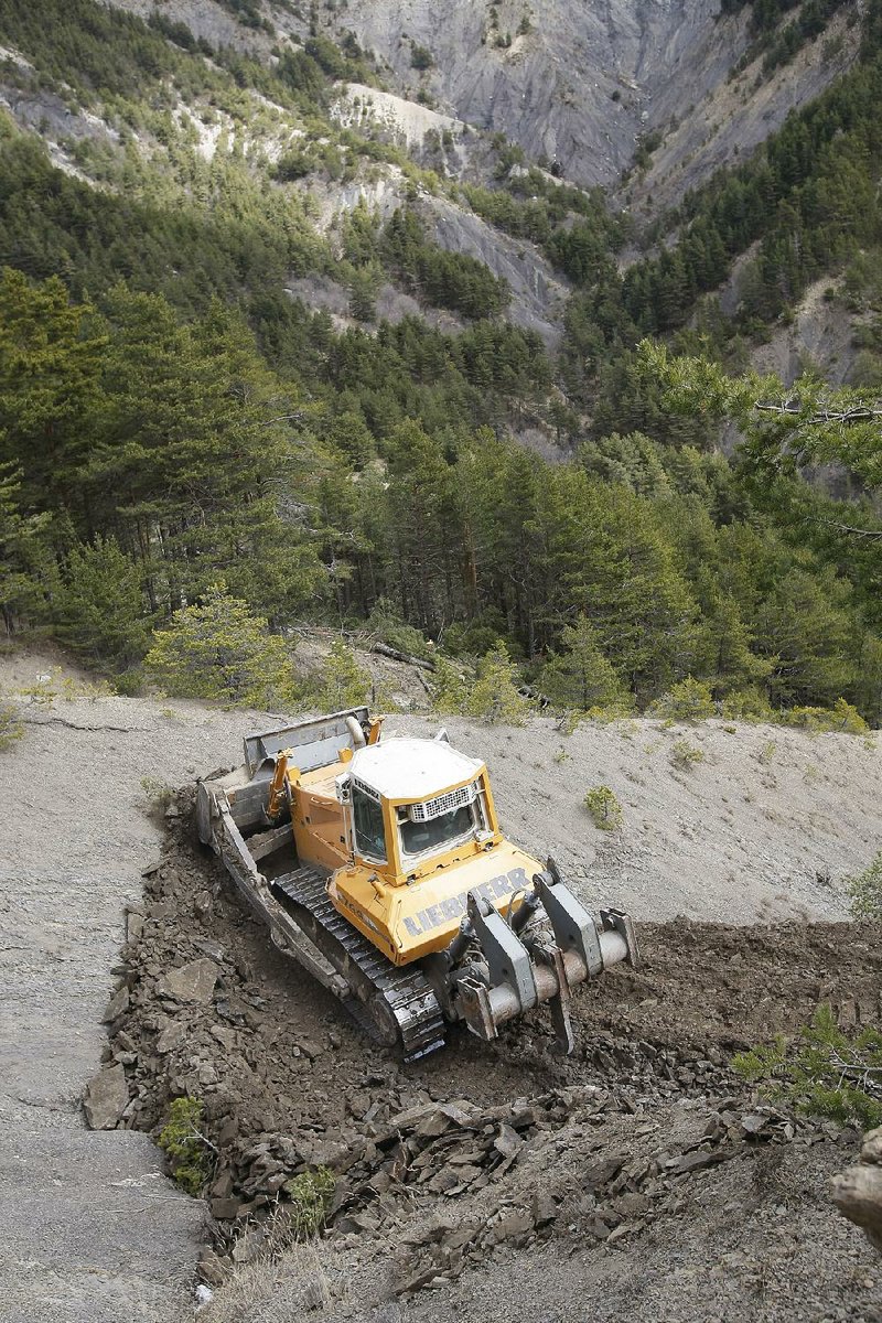 A bulldozer clears a path to the crash site near Seyne-les-Alpes, France, Monday, March 30, 2015.  European investigators are focusing on the psychological state of a 27-year-old German co-pilot who prosecutors say deliberately flew a Germanwings plane carrying 150 people into a mountain, a French police official said Monday. (AP Photo/Claude Paris, Pool)