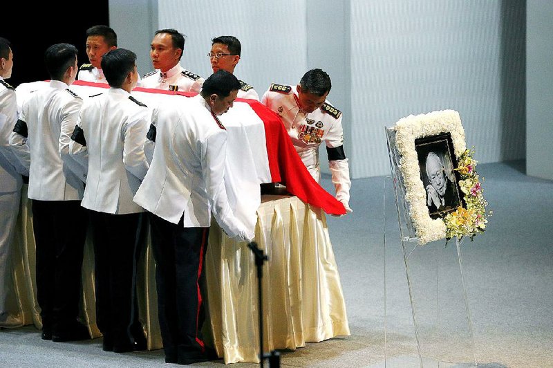 Pallbearers adjust the national flag of Singapore covering the coffin of the late Lee Kuan Yew during a state funeral held at the University Cultural Center, Sunday, March 29, 2015, in Singapore. During a week of national mourning that began Monday after Lee's death at age 91, some 450,000 people queued for hours for a glimpse of Lee's coffin at Parliament House. A million people visited tribute sites at community centers across the island and leaders and dignitaries from more than two dozen countries attended the state funeral. (AP Photo/Wong Maye-E)