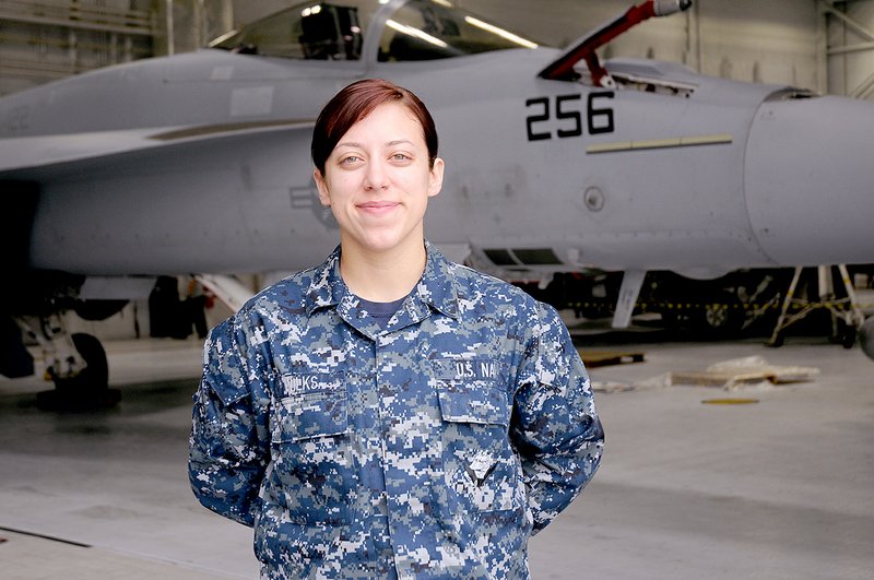 Photo by U.S. Navy Airman Makayla Wilks of Siloam Springs, an aviation electrician&#8217;s mate in the U.S. Navy, standing near the Navy&#8217;s strike fighter aircraft, the F/A-18E/F Super Hornet.