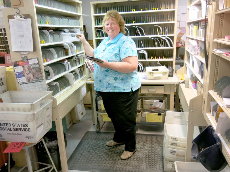 Photo by Susan Holland Gravette rural mail carrier Michelle Howard spends time in her cubicle sorting letters before leaving to deliver mail each morning. She recently saved a house from burning while out on her daily route east of town.