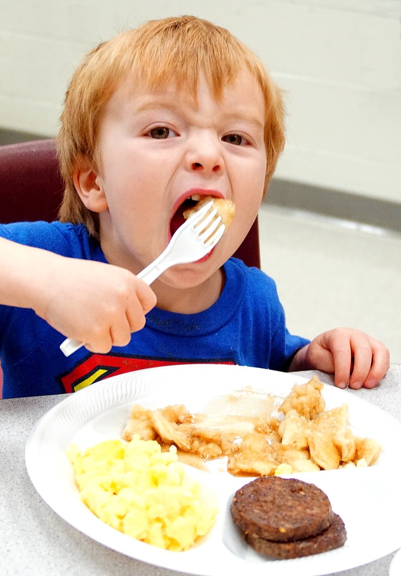 Photo by Randy Moll Deacon DuBois, 3, puts a fork full of pancakes into his mouth Monday at the annual Gentry Lions Club Pancake Supper. Money raised at the supper is slated to go for the support of local sight projects.