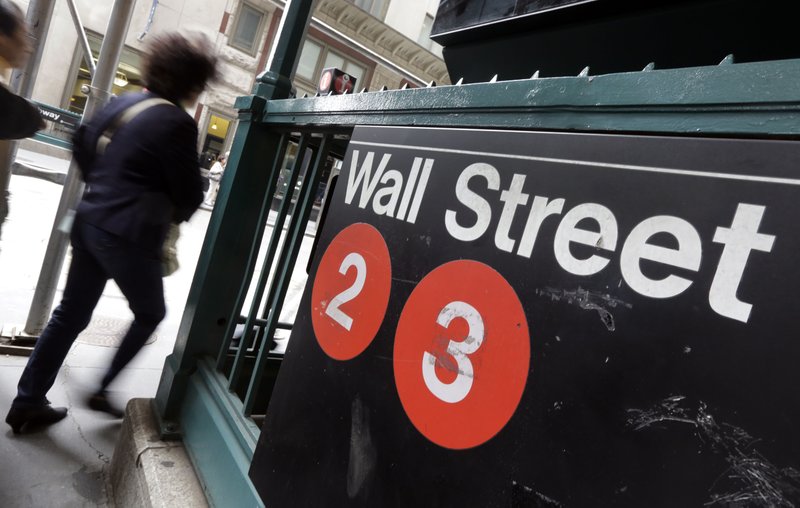 In this Oct. 2, 2014 file photo, people pass a Wall Street subway stop, in New York's Financial District. U.S. stocks moved lower in early trading Tuesday, March 31, 2015, erasing some gains from the day before.