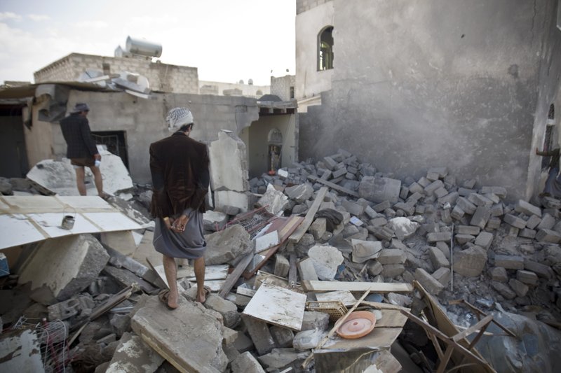 Yemeni men inspect their houses destroyed by Saudi airstrikes near Sanaa Airport, Yemen, Tuesday, March 31, 2015. 