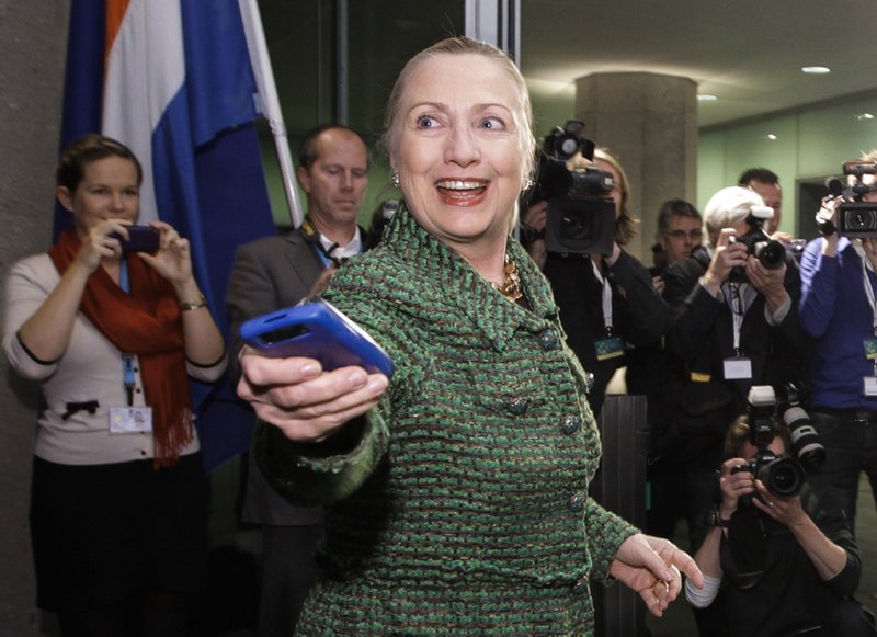 In this Dec. 8, 2011, file photo, then-U.S. Secretary of State Hillary Rodham Clinton hands off her mobile phone after arriving to meet with Dutch Foreign Minister Uri Rosenthal at the Ministry of Foreign Affairs in The Hague, Netherlands. Clinton emailed her staff on an iPad as well as a BlackBerry while secretary of state, despite her explanation that she exclusively used a personal email address on a homebrew server so she could carry a single device, according to documents obtained by The Associated Press. 