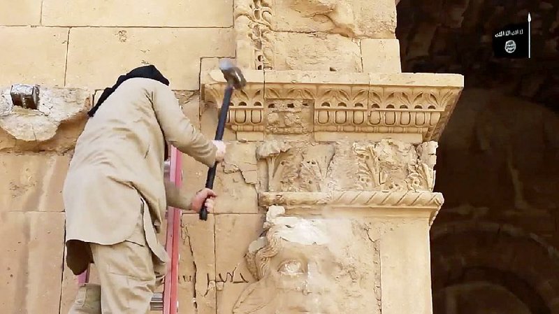 In an image taken from a video posted Friday on YouTube, a member of the Islamic State hammers away at a face on a wall in Hatra, Iraq. The archaeological site in the city, recognized as a UNESCO World Heritage site, was destroyed. 