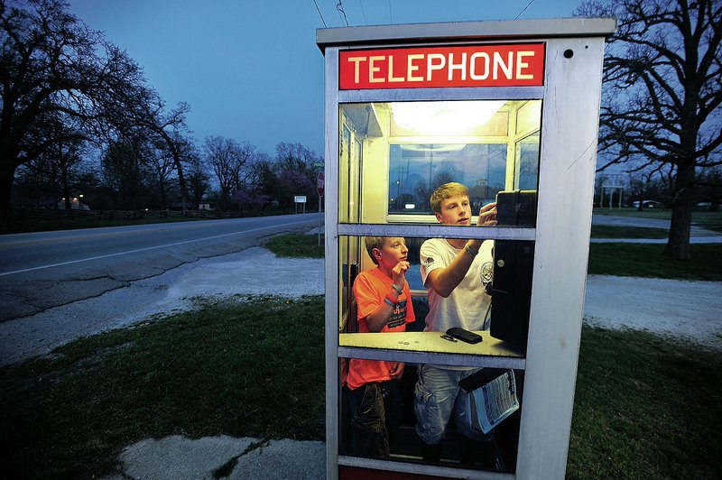 Mason McCourt, 13, (left) and Blake Williams, 14, call friends Thursday from the pay telephone booth across from Prairie Grove Battlefield State Park. 