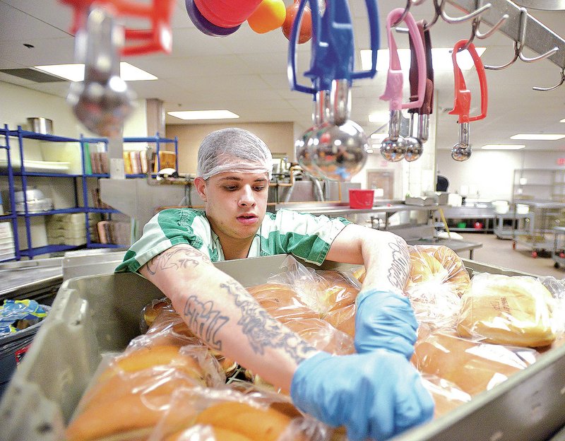 NWA Democrat-Gazette/BEN GOFF Dalton Easley of Rogers unwraps hot dog buns Thursday as trusties prepare the evening meal at the Benton County Jail in Bentonville. The change to hot meals was recommended in Arkansas&#8217; revised criminal detention facility standards Jan. 5. Benton County&#8217;s jail is one the the last to serve hot meals.