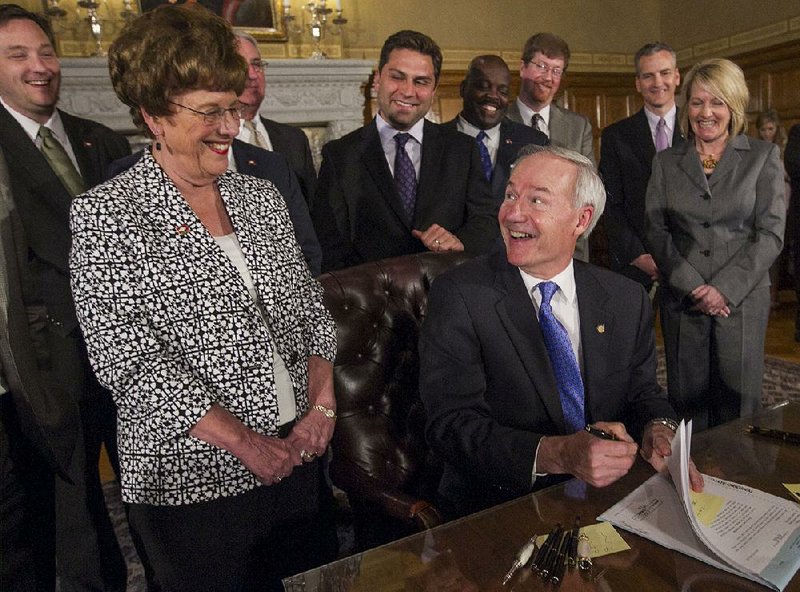 Arkansas Democrat-Gazette/BENJAMIN KRAIN --04/06/2015-- 
Gov. Asa Hutchinson signs into law three state Senate bills aimed at overhauling the state's workforce education programs during a ceremony Monday at the Capitol as legislators look on. Sen. Jane English, R-North Little Rock, at left, sponsored 2 of the 3 bills which create a grant program, an Office of Skills Development and sets legislative language that will allow the state to maximize opportunities for federal grants.