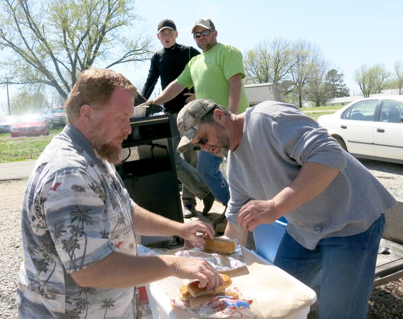 Photo by Susan Holland Dennis Berry and David Poulter put hot dogs in buns for the hungry egg hunters at Saturday&#8217;s event sponsored by Church on the Hill. Cooks Donnie Lemonds and Matt Croxdale, at the grill, said they prepared 180 hot dogs to feed the group which came out.