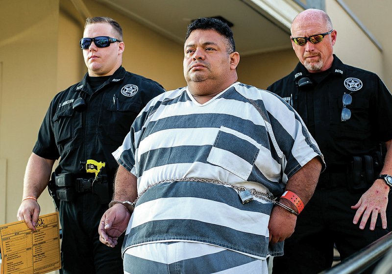 Mauricio Alejandro Torres, 45, is led out of Judge Brad Karren’s court Tuesday in Bentonville. Torres and Cathy Lynn Torres, 43, both of Bella Vista, were arrested Monday in connection with capital murder in the death of their 6-year-old son. Karren ordered the couple be held in the Benton County Jail without bond.