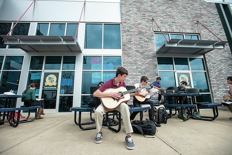 NWA Democrat-Gazette/ANTHONY REYES &#8226; @NWATONYR Ben Morrison, Haas Hall senior, plays an acoustic guitar Tuesday outside the school in Fayetteville. Morrison joined the rest of his instrumental class in playing outdoors in the warm weather. For photo galleries, go to nwadg.com/photos.