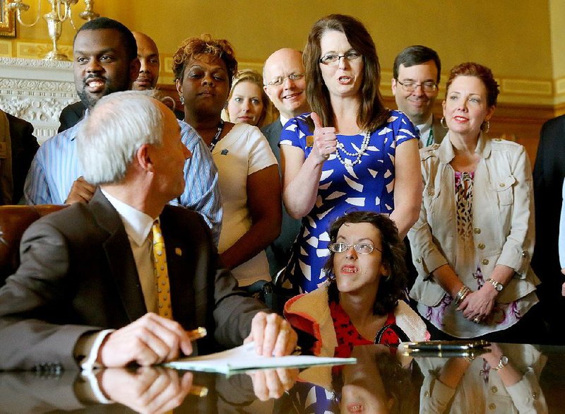 State Rep. Julie Mayberry, R-Hensley, gives Gov. Asa Hutchinson (seated, left) a thumbs up Wednesday moments before Hutchinson signed House Bill 1239. Mayberry sponsored the legislation, which is intended to “provide new avenues for financial self-sufficiency for Arkansans with disabilities.” 