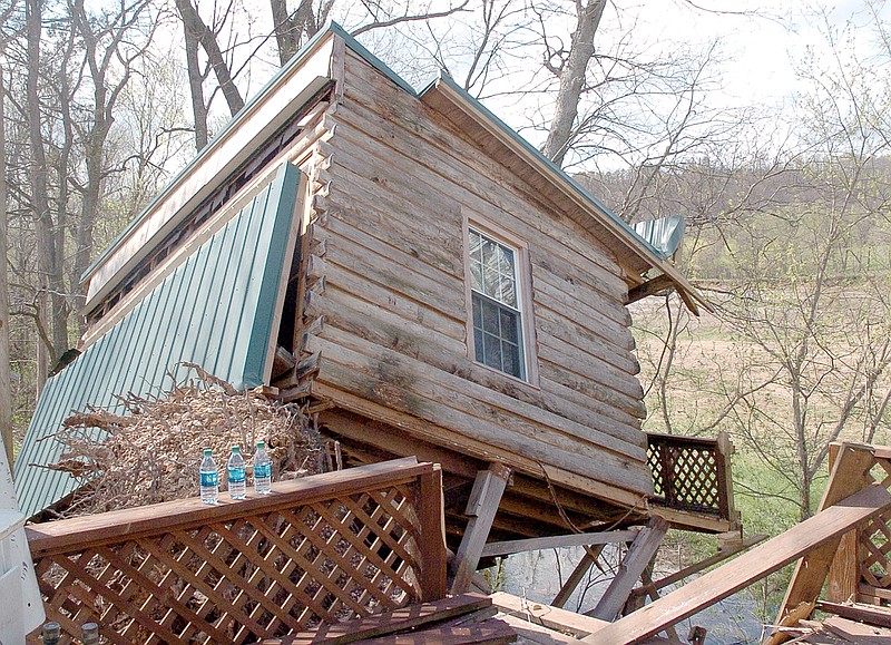 RICK PECK MCDONALD COUNTY PRESS A cabin at the Randy and Paw Cowger residence, located on Route H west of Pineville, tips precariously on a hill overlooking the Elk River following an April 2 severe storm.