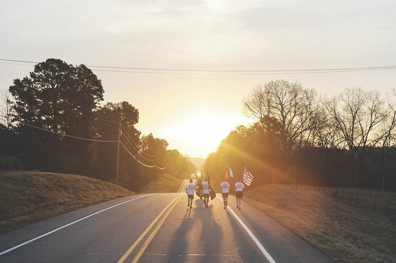 The second team of runners carries flags on its leg of the Arkansas Run for the Fallen on March 20 at Altus. Twenty-one four-man teams participated in the event by running and carrying the American flag and the Arkansas state flag, as well as smaller American flags that had fallen Arkansans’ bios attached to the flags.