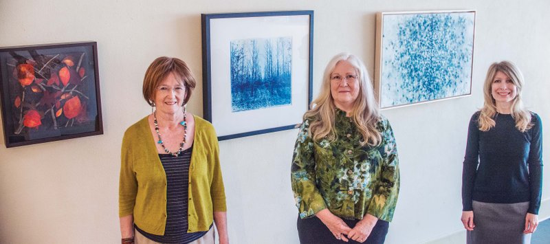 The Arkansas Committee of the National Museum of Women in the Arts has included three Hot Springs artists in its online registry. They include, from left, Barbara Cade, with a piece of her fiber art, Red Leaves, left; Beverly Buys with her photograph Moody Place, behind her; and Dolores Justus with her oil painting Diffusion, shown behind her.