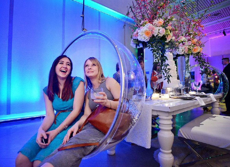Burgundy Wisrock (left) of Bentonville and Kaci Alterici of Fayetteville try one of the hanging chairs in a decor setup at the Ultimate Wedding Experience. The four decor spaces exhibited a few wedding styles available for brides at the 21c Museum Hotel. 