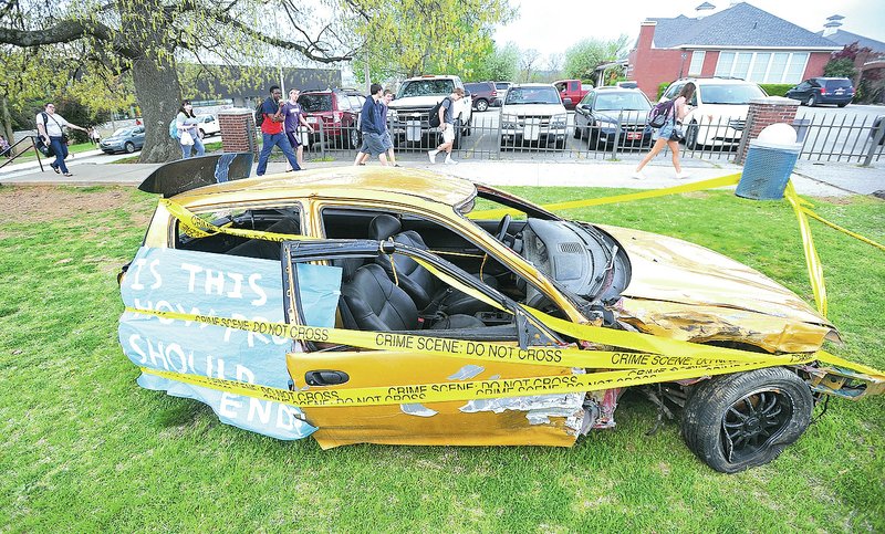NWA Democrat-Gazette/MICHAEL WOODS &#8226; @NWAMICHAELW Fayetteville High School students walk past a wrecked car set up in front of the school Thursday in Fayetteville. Students set up the crashed car to educate students about the dangers of driving while under the influence of drugs or alcohol.