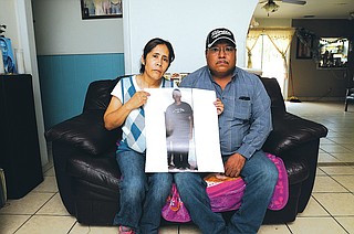 NWA Democrat-Gazette/J.T. WAMPLER Hipolito and Ophelia Rodriguez hold a photograph Thursday of their son, Fabian, who was shot and killed March 13. His family says they never thought for a moment Fabian, their fourth child among 10, was in gang activity.
