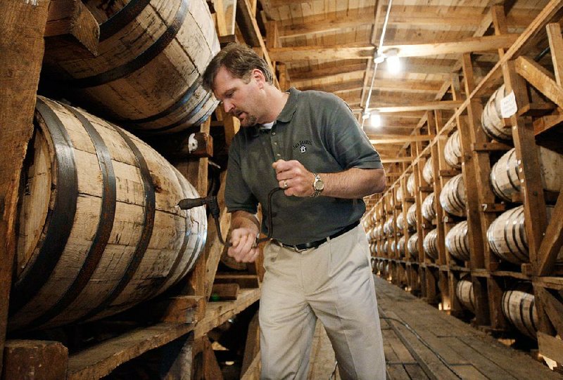 FILE – In this May 20, 2009, file photo, Jeff Arnett, the master distiller at the Jack Daniel Distillery in Lynchburg, Tenn., drills a hole in a barrel of whiskey in one of the aging houses at the distillery. The sponsor of a bill seeking to repeal the Jack Daniel's-endorsed law establishing requirements for which spirits can be sold as Tennessee Whiskey withdrew the measure on Tuesday, April 7, 2015.  (AP Photo/Mark Humphrey, File)