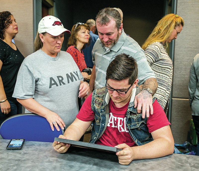 NWA Democrat-Gazette/ANTHONY REYES &#8226; @NWATONYR Dallas Howell (seated), 17, Har-Ber junior, looks at his certificate for completion of a National Center for Construction Education and Research program with his parents Aimee Gremard and Jeff Howell Thursday, April 9, 2015 at a ceremony for Har-Ber students at the school in Springdale. The students were trained in best practices for safety and procedures and the program offers training in multiple craft areas to help support the job needs of local businesses.