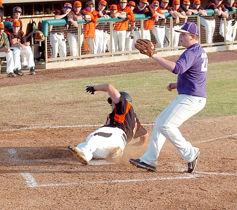 Photo by Mike Eckels Gravette&#8217;s Luke Summerford (#11) slides across home plate as the Berryville pitcher covers during the April 9 game at Lion Field. An error by the Bobcat catcher allowed Summerford to score. The Lions defeated the Bobcats, 11 to 1.