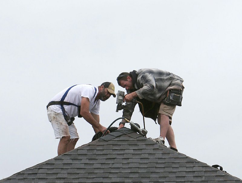 In this March 24, 2015 photo, roofers work on a new home in Panama City, Fla. The Federal Reserve releases its Beige Book report on Wednesday, April 15, 2015. 