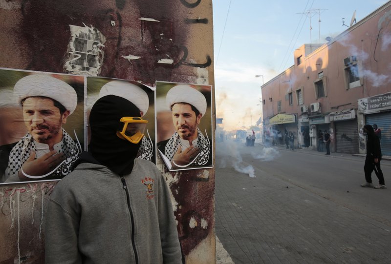 In this Jan. 20, 2015, file photo, a Bahraini anti-government protester watches clashes between protesters and police firing tear gas and shotguns, in Bilad al-Qadeem, Bahrain. Government reforms put in place by Bahraini authorities in the wake of widespread anti-government protests four years ago have failed to end serious violations of human rights in the strategically important Gulf nation, Amnesty International said in a report released Thursday, April 16, 2015.