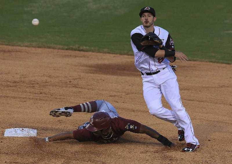 Arkansas shortstop Eric Stamets (right) throws to first base after forcing out Frisco runner Nick Williams during the Travelers’ home opener Thursday night in North Little Rock. Frisco put an end to Arkansas’ six-game winning streak with a 2-0 victory.