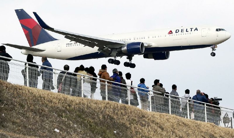 Plane spotters in Sakuranoyama Park east of Tokyo watch a Delta Air Lines jet land last month at the Narita International Airport. Delta, the first of the major U.S. carriers to release first-quarter earnings, reported a profit Wednesday of $372 million. 