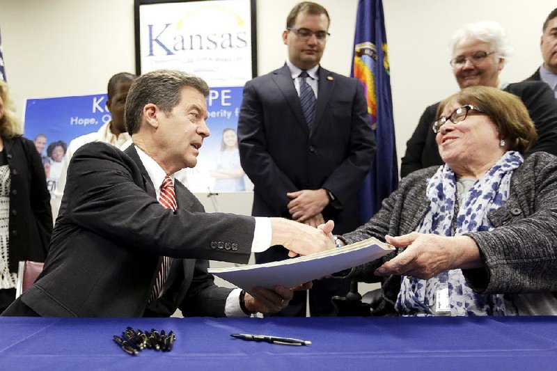 Kansas Gov. Sam Brownback acknowledges Phyllis Gilmore, secretary of the state’s Department for Children and Families, after signing a welfare overhaul bill Thursday in Topeka. 