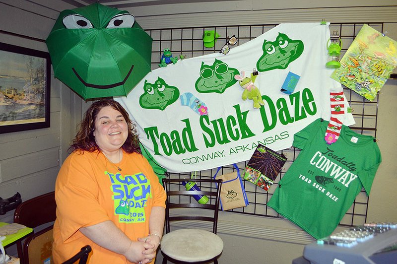 Toad Store employee Tiffany Thornton stands in front of a display of items for sale, including a beach towel, an umbrella and one of three designs of T-shirts offered this year. Toad Suck Daze is scheduled for May 1-3 in downtown Conway. The Toad Store, at 1321 Oak St. in Conway, is open from 10 a.m. to 3 p.m. Saturdays; 11 a.m. to 3 p.m. Sundays; and 11 a.m. to 6 p.m. Tuesday through Friday.