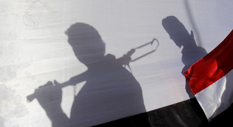 The shadow of Shiite rebels, known as Houthis, are cast on a large representation of the Yemeni flag as they attend a demonstration against an arms embargo imposed by the U.N. Security Council on Houthi leaders, in Sanaa, Yemen, Thursday, April 16, 2015. 