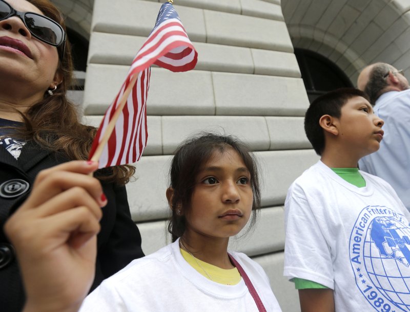 Ebenyn Roca, 9, of Miami, holds an American flag participates in a rally led by the New Orleans Worker Center for Racial Justice and the Congress of Day Laborers, outside the U.S. Fifth Circuit Court of Appeals in New Orleans, Friday, April 17, 2015. 