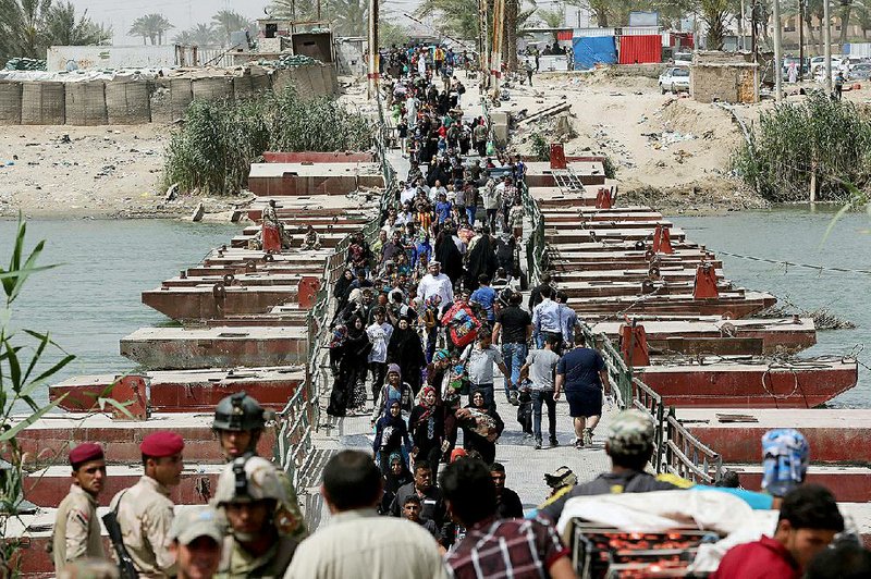 People fleeing Ramadi in western Iraq cross a bridge about 50 miles west of Baghdad on Saturday. Iraqi government forces reportedly were arriving at Ramadi to battle Islamic State militants. 