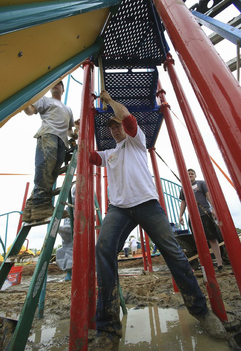 Volunteers Todd Mazza (left) of Chicago and Jacob Simon of Vilonia assemble playground equipment Saturday at a park in Vilonia. The new playground was sponsored by the nonprofit Kaboom and by Kimberly-Clark Corp.