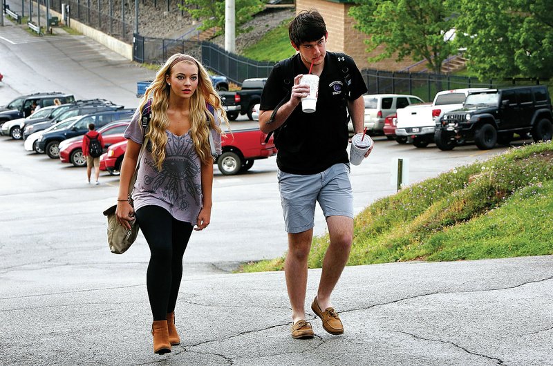 NWA Democrat-Gazette/DAVID GOTTSCHALK Brittany Lyons (left) and Colton Farley, both juniors at Fayetteville High School, walk up from the lower parking lot Friday after arriving at school in Fayetteville. The school is looking at parking options both on and off of the campus following the completion of the renovation projects.