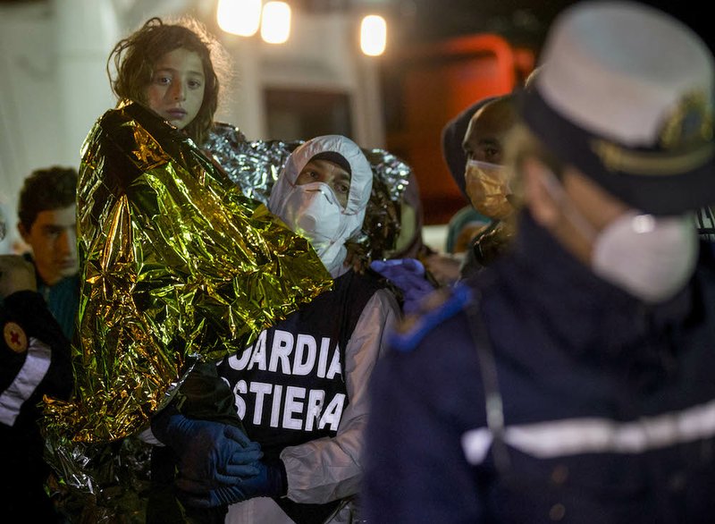 A migrant is helped disembark in the Sicilian harbor of Pozzallo, Italy, early Monday, April 20, 2015. About 100 migrants, including 28 children, were rescued Sunday by a merchant vessel in the Sicilian Strait while they were trying to cross. 