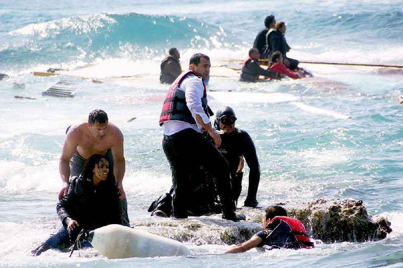 A man rescues an migrant from the Aegean sea, in the eastern island of Rhodes, Monday, April 20, 2015. Greek authorities said that at least three people have died, including a child, after a wooden boat carrying tens of migrants ran aground off the island of Rhodes. (Argiris Mantikos/Eurokinissi via AP) GREECE OUT