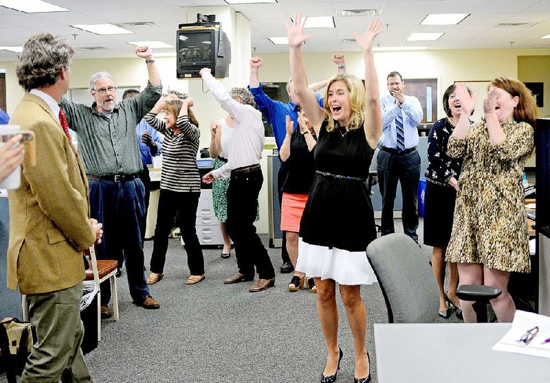 The Post and Courier staff, including publisher P.J. Browning, cheers after the Pulitzer announcement Monday, April 20, 2015 in Charleston, S.C. The newspaper was awarded a Pulitzer Prize for Public Service for its series on domestic violence. The Public Service gold medal went to reporters Doug Pardue, Glenn Smith, Jennifer Berry Hawes and Natalie Caula Hauff for the series “Till Death Do Us Part.” The series explored the deaths of 300 women in the past decade and a legal system in which abusers face at most 30 days in jail if convicted of attacking a woman, while cruelty to a dog can bring up to five years in prison.   (Matthew Fortner/The Post And Courier via AP)