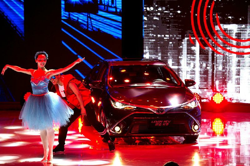 Dancers introduce the latest car from Japanese automaker Toyota at the Shanghai Auto Show in Shanghai Monday, April 20, 2015. Ford showed off its new Taurus and Nissan unveiled a midsize sedan designed for China on Monday at the exhibition that highlighted the commercial resurgence of lower-priced Chinese auto brands. (AP Photo/Ng Han Guan)