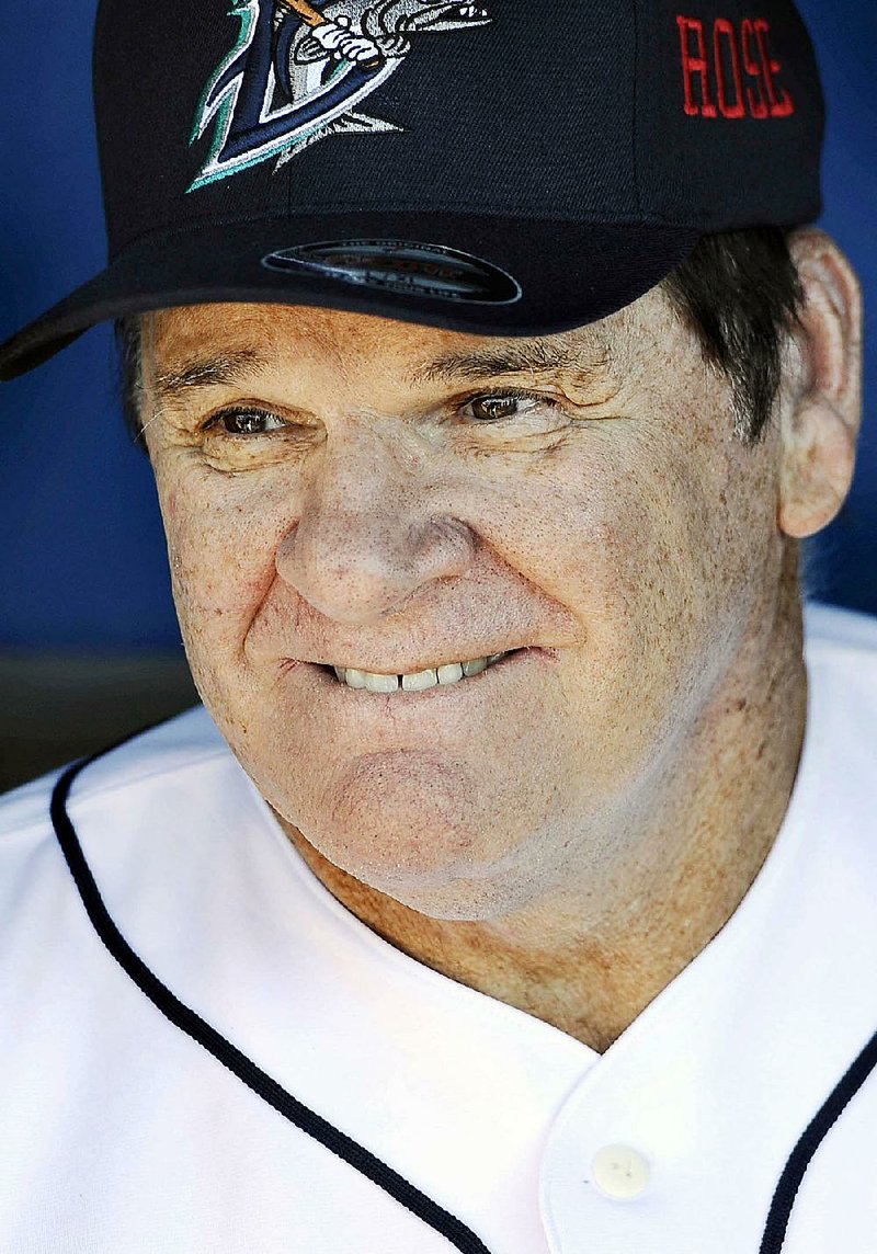 FILE - In hits June 16, 2014, file photo, Pete Rose smiles while sitting in the dugout at The Ballpark at Harbor Yard in Bridgeport, Conn., before he managed the independent minor-league Bridgeport Bluefish in a baseball game. Fox Sports said Saturday, April 18, 2015, that it was hiring Rose, the career hits leader, as a special guest analyst. Rose agreed to the lifetime ban from baseball in August 1989 after a Major League Baseball investigation concluded he bet on the Cincinnati Reds to win while managing the team. (AP Photo/Jessica Hill, File)
