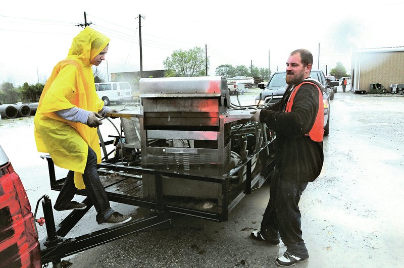 File Photo/NWA Democrat-Gazette/FLIP PUTTHOFF Kayla Summey (left) and Sean Smith work in the rain Saturday during the county cleanup event at the Road Department in Bentonville. Hundreds took advantage of the service to dispose of bulk items, electronics, paint, prescription drugs and more free of charge.